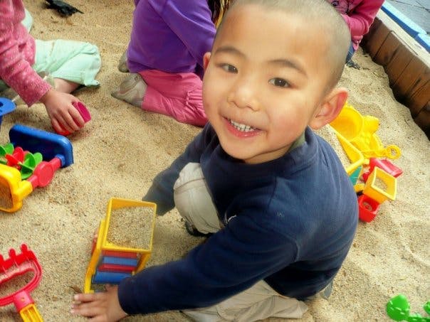 Child playing in a sandbox with toys