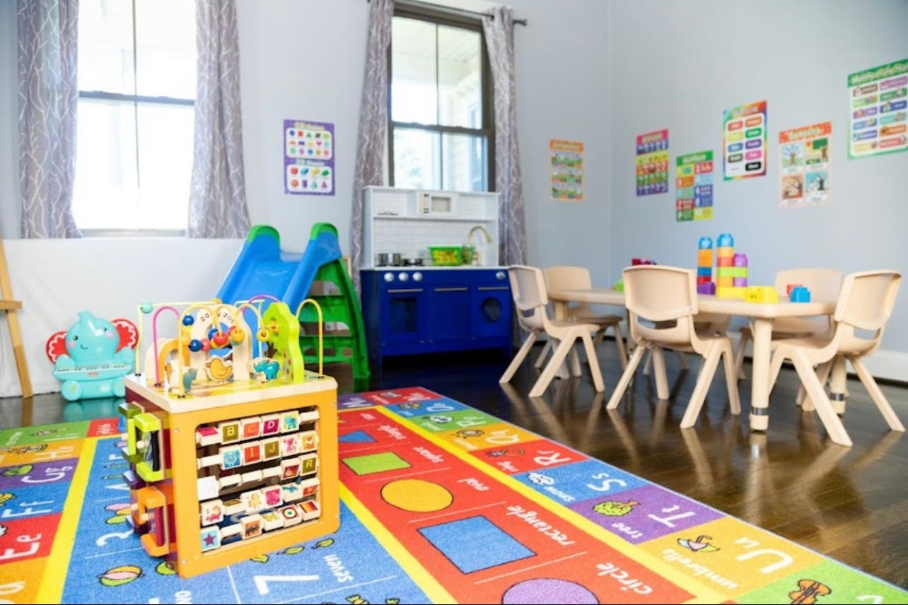 Playroom with a colorful rug, activity cube, slide, and small table with chairs