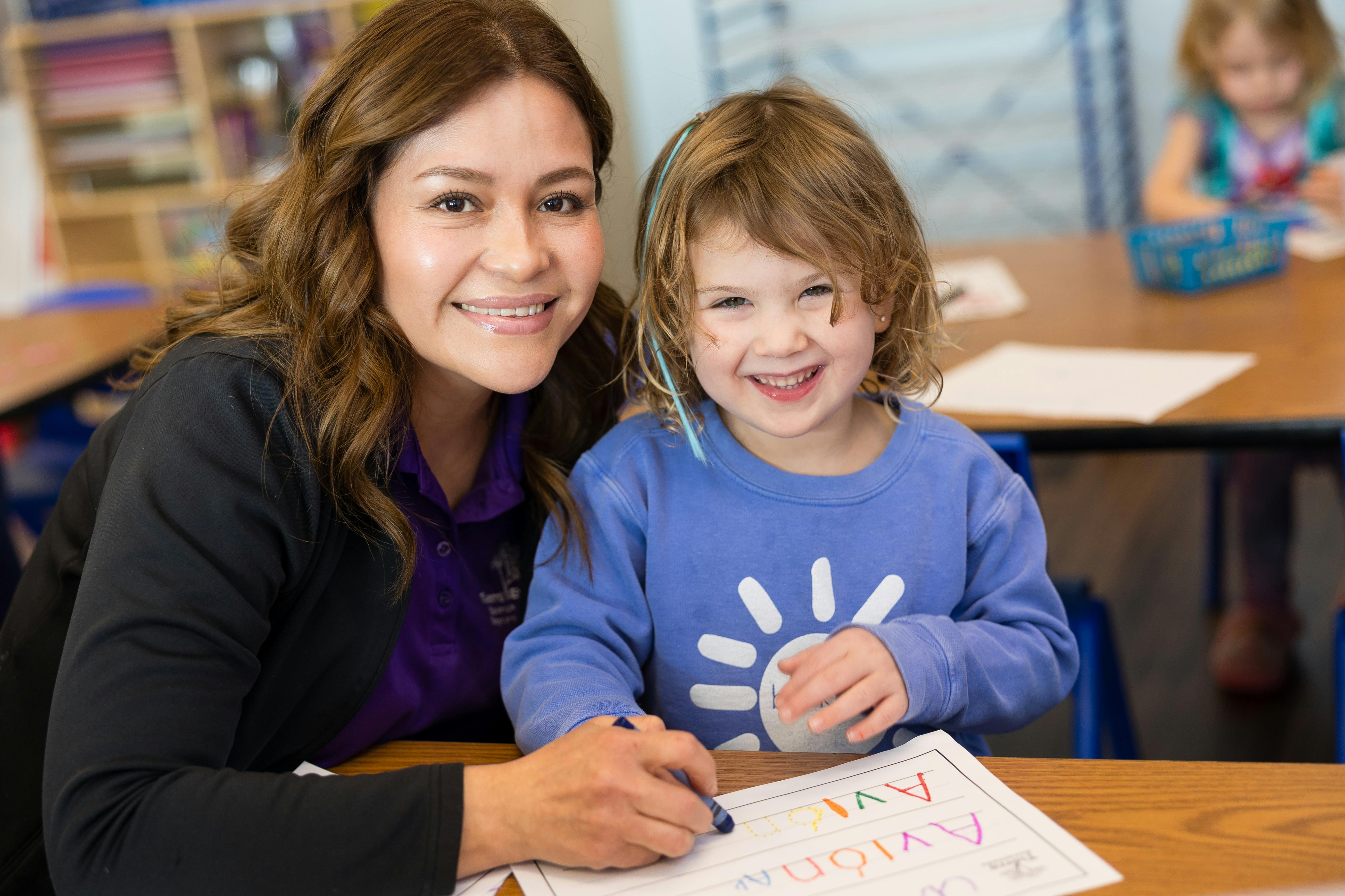 Adult and child coloring a workbook in a classroom