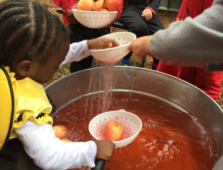 Children washing apples in a large tub of water