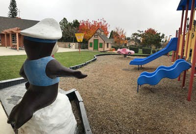 Statue of a character in a sailor hat looking at a playground with slides