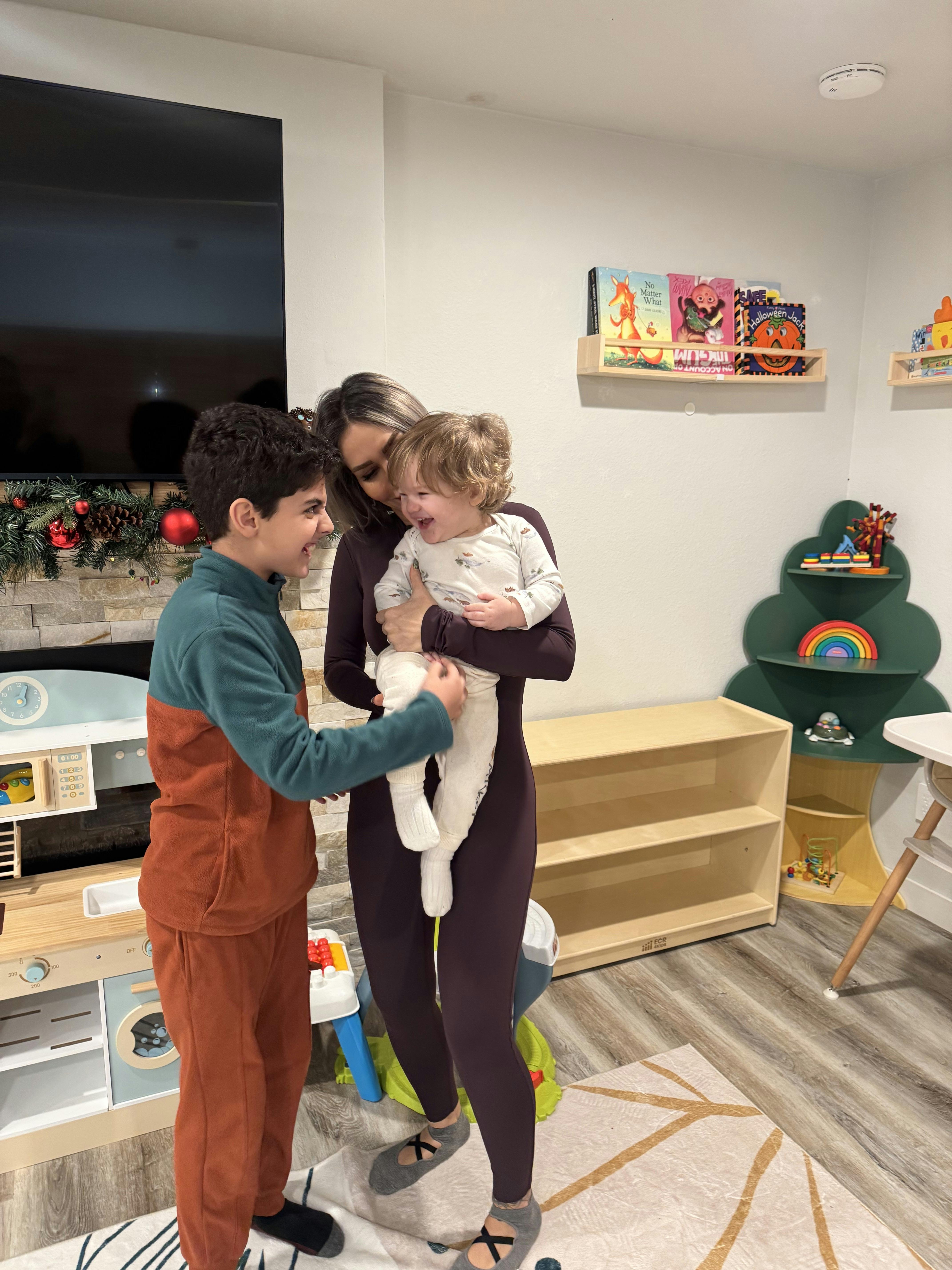 adult holding a child while a teen interacts with the child