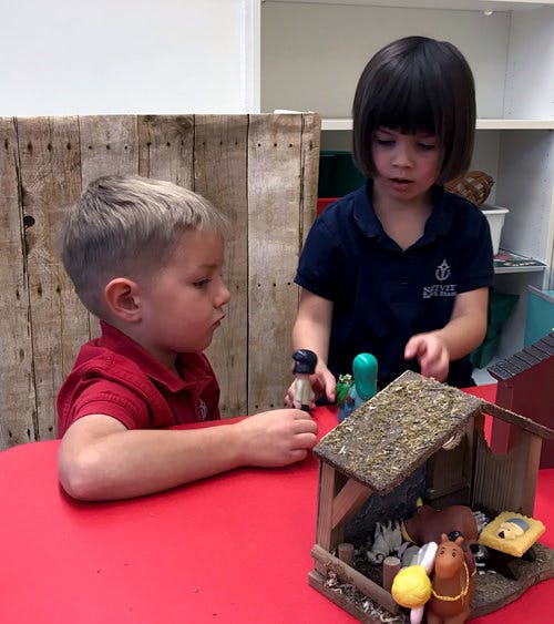 Two children playing with a toy stable and a small stable