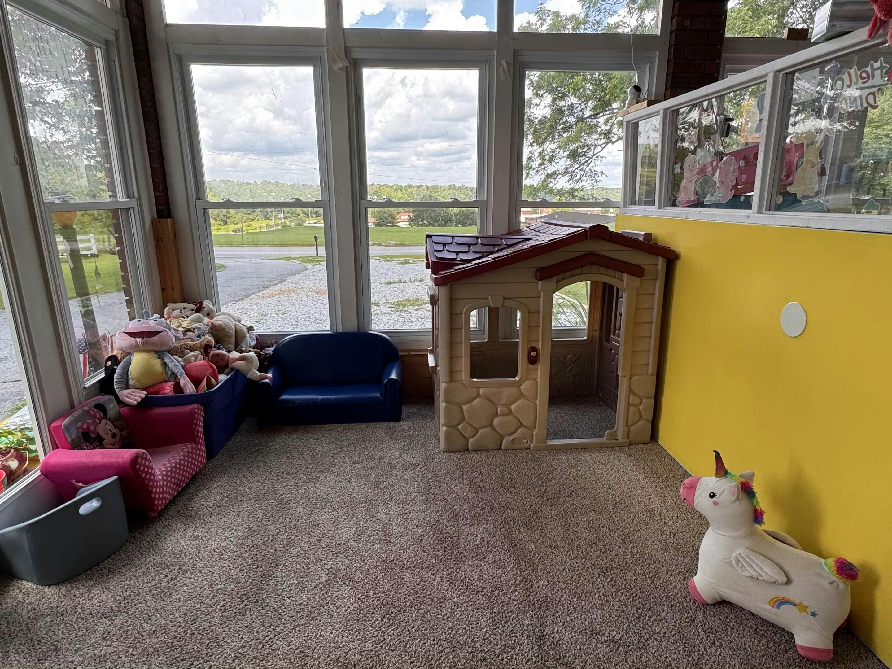 Playroom with toy house, small couches, and stuffed animals