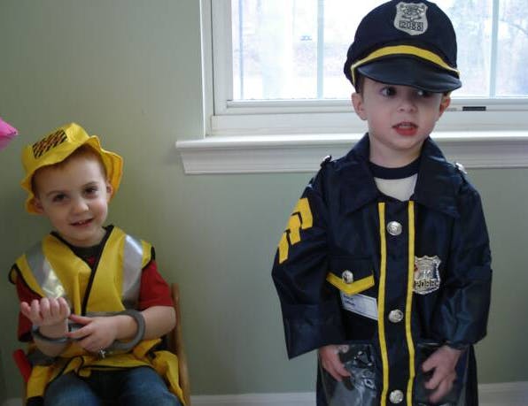 Two children in costumes, one in a police uniform and one in a construction vest