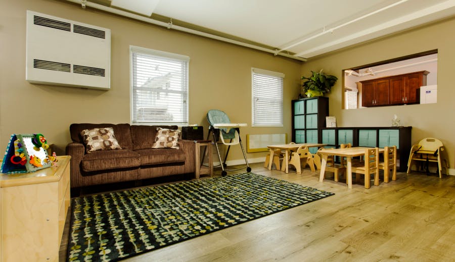 Living room with a sofa, rug, and small tables with chairs