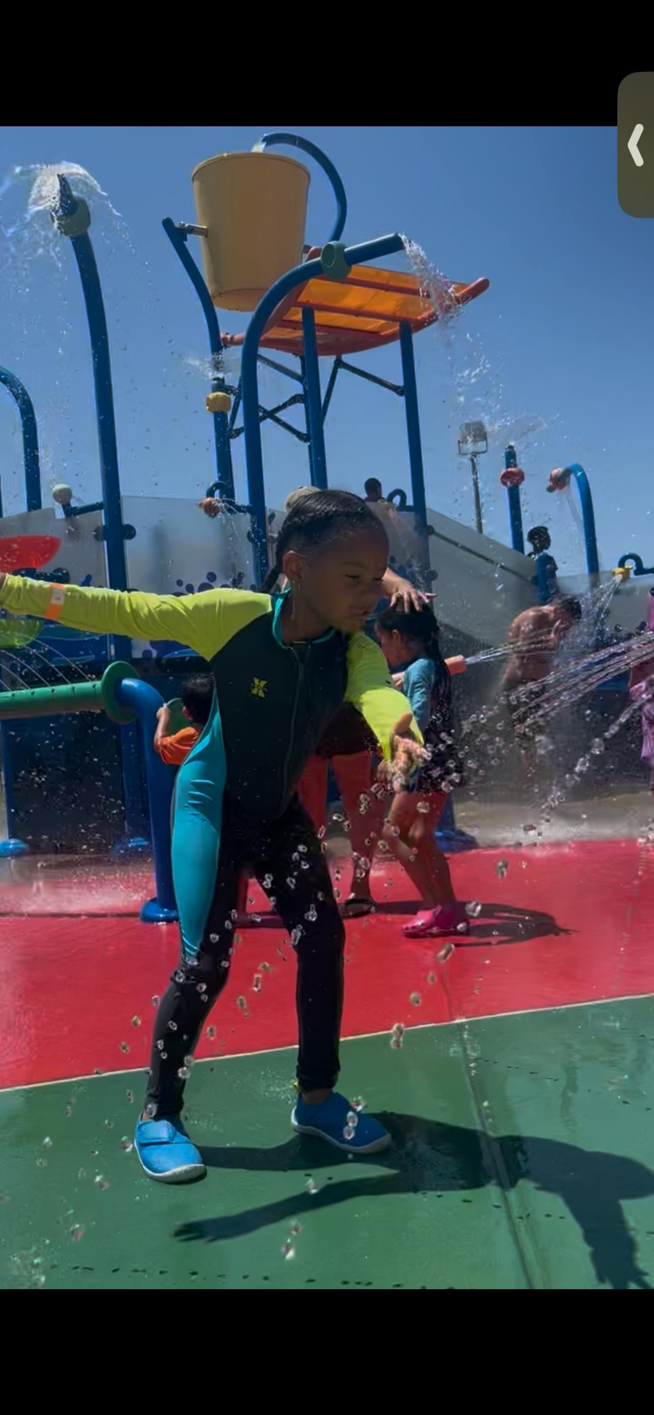 Child in a swimsuit playing in a splash pad with water spraying