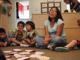 Person sitting on floor with children in a classroom