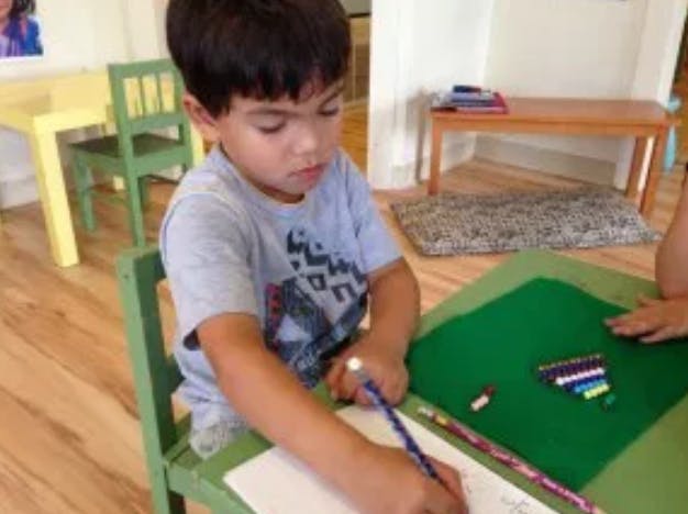 Child drawing with a pencil at a table