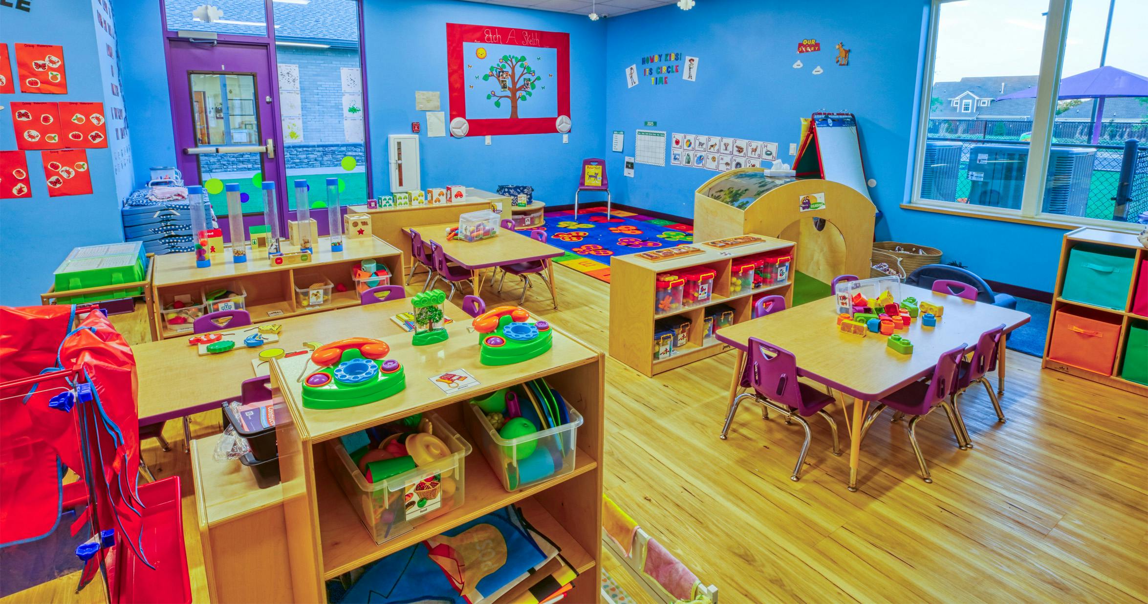 Classroom filled with child-sized tables, chairs, shelving units, and toys