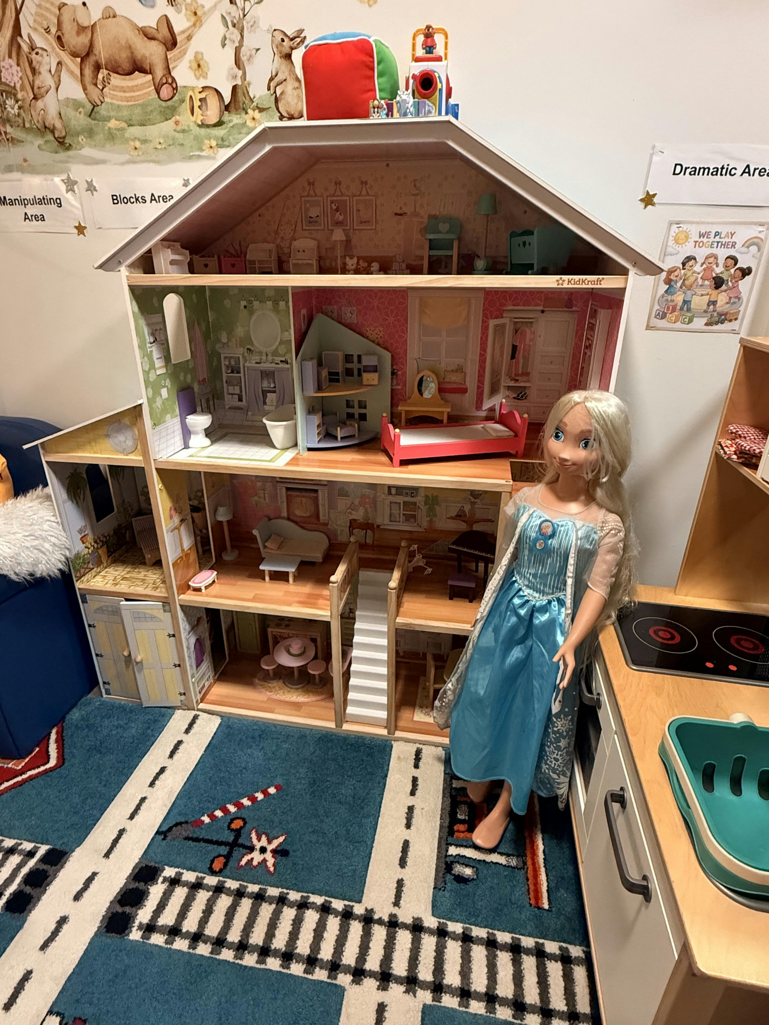 Dollhouse in a play area next to a large character doll