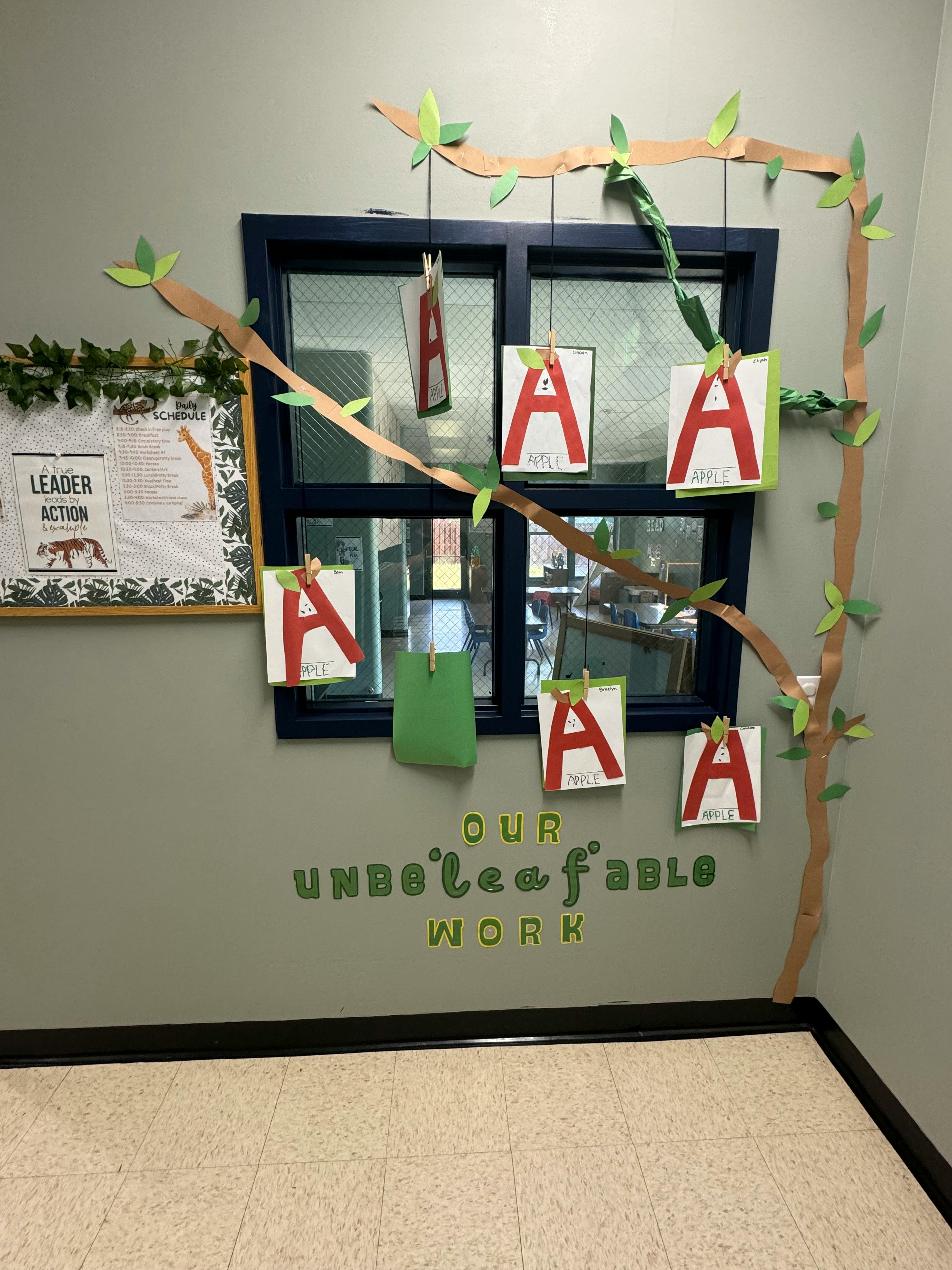 Wall decoration with paper vines, window, and papers with the letter A