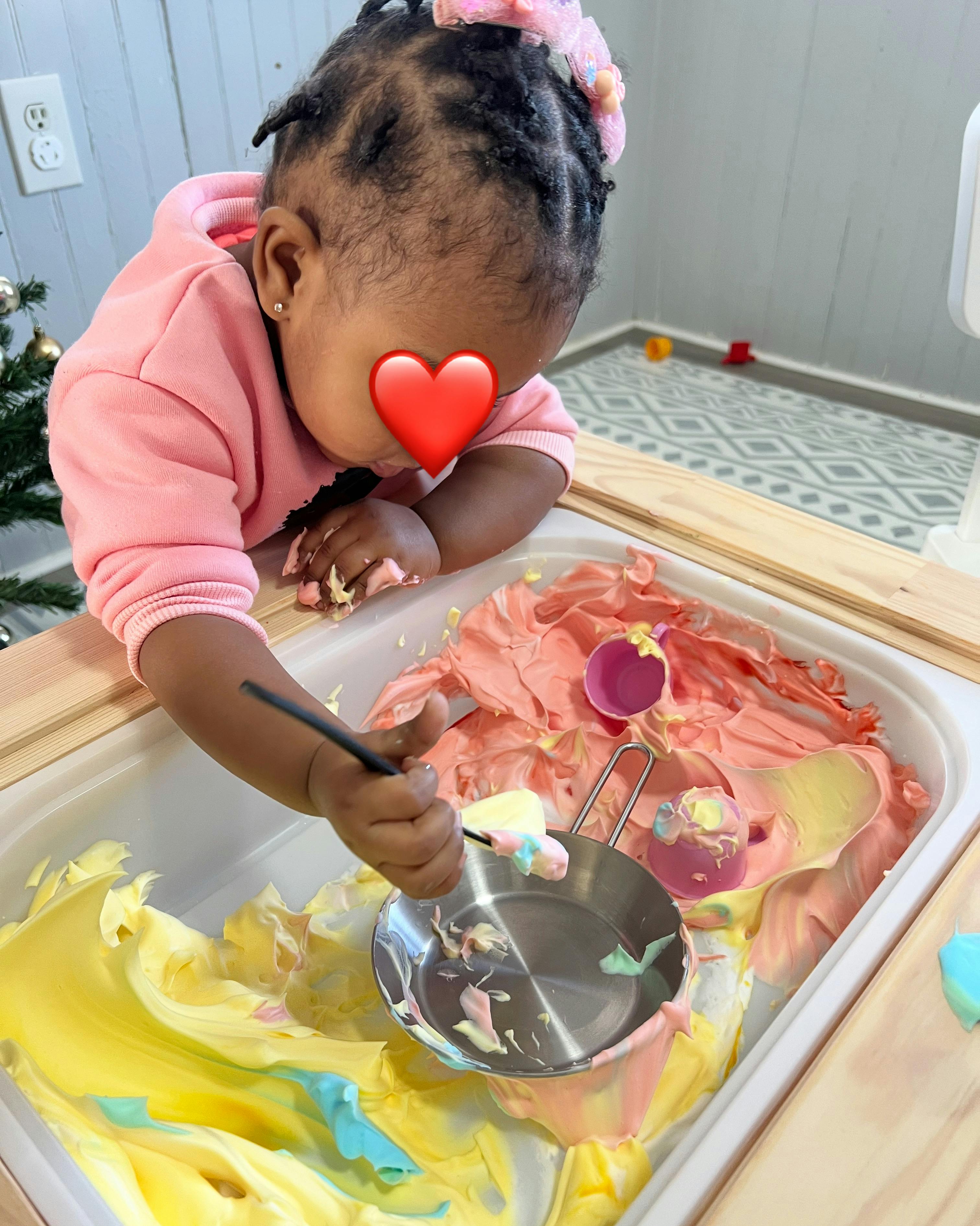 Child playing with colorful sensory foam and toy kitchen utensils