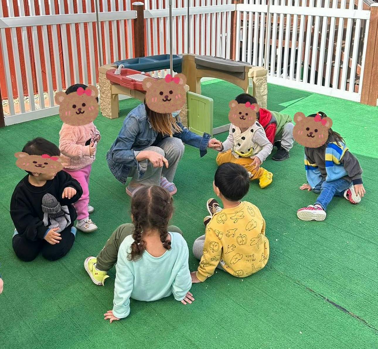Adult interacting with children on a green surface