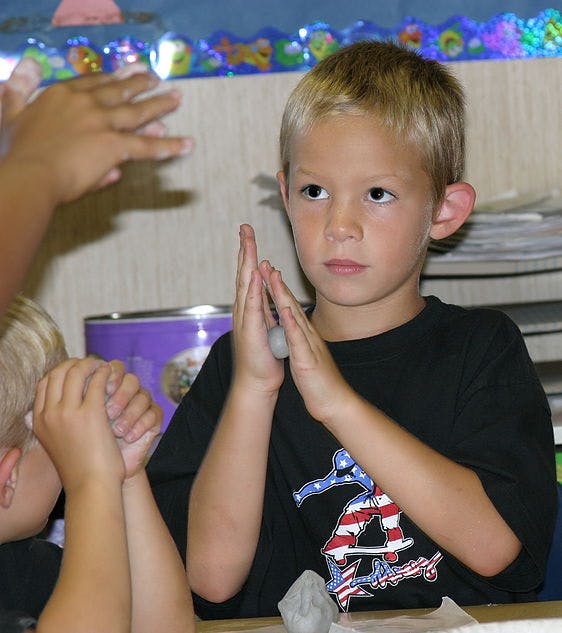 Child rolling clay in hands