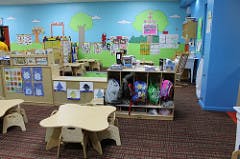 Classroom with small tables and chairs, colorful wall mural