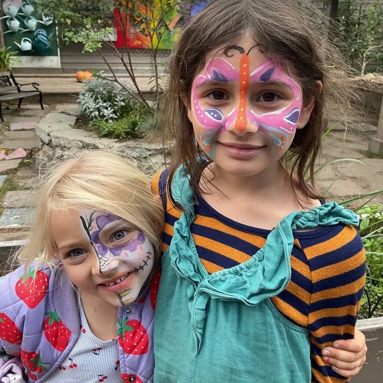 Two children with face paint, one with a butterfly design, the other with a skull