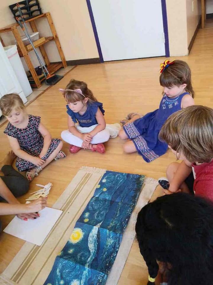 Children sitting on the floor looking at a painting