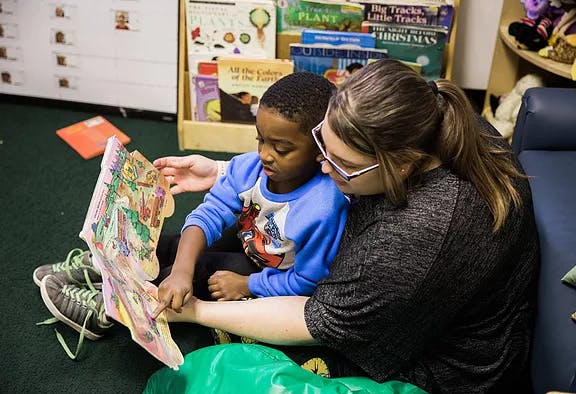 Person and child reading a book together