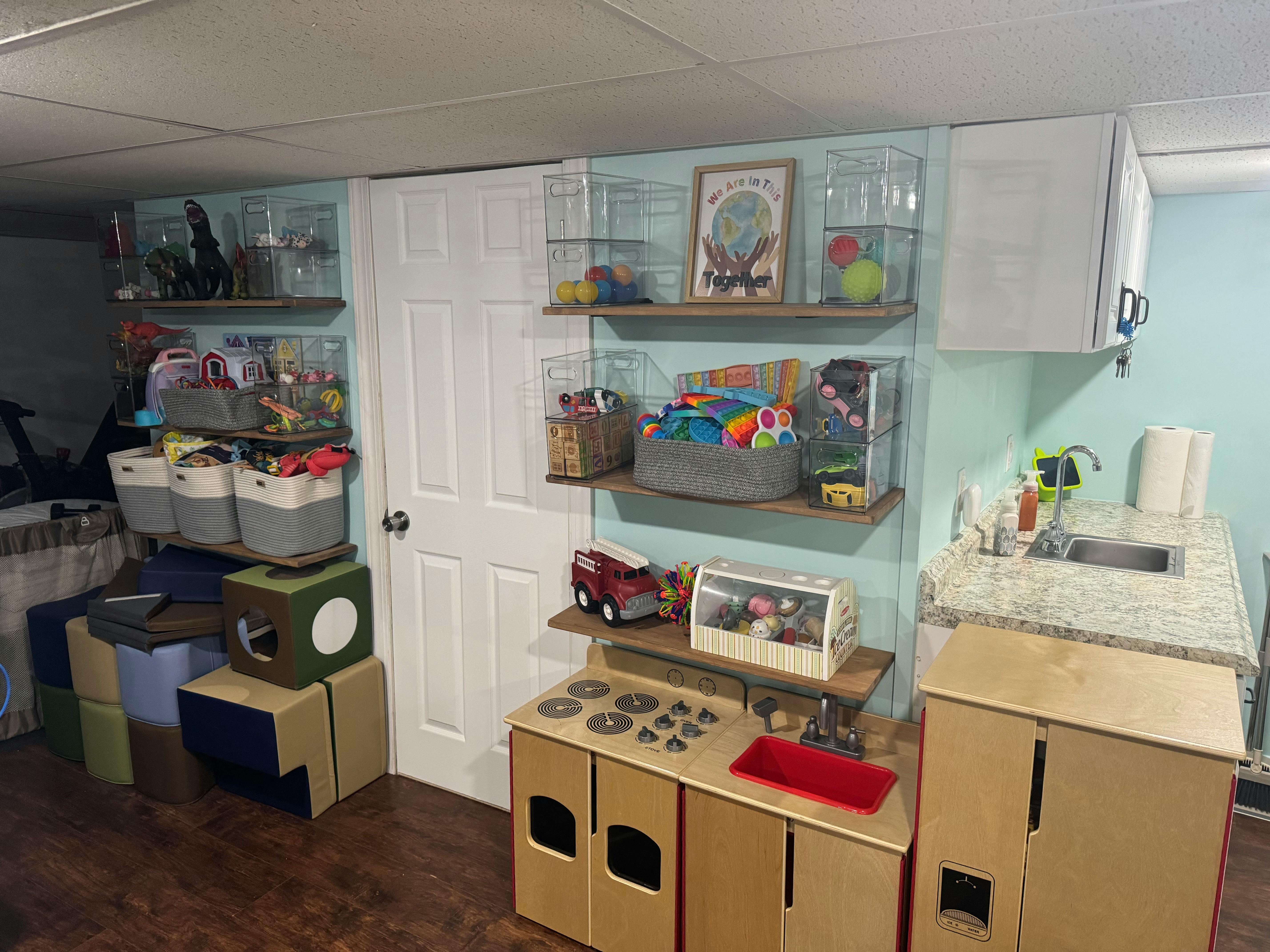 Playroom with shelves of toys, a play kitchen, and a small sink area