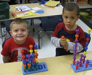 Two children playing with colorful building toys at a table