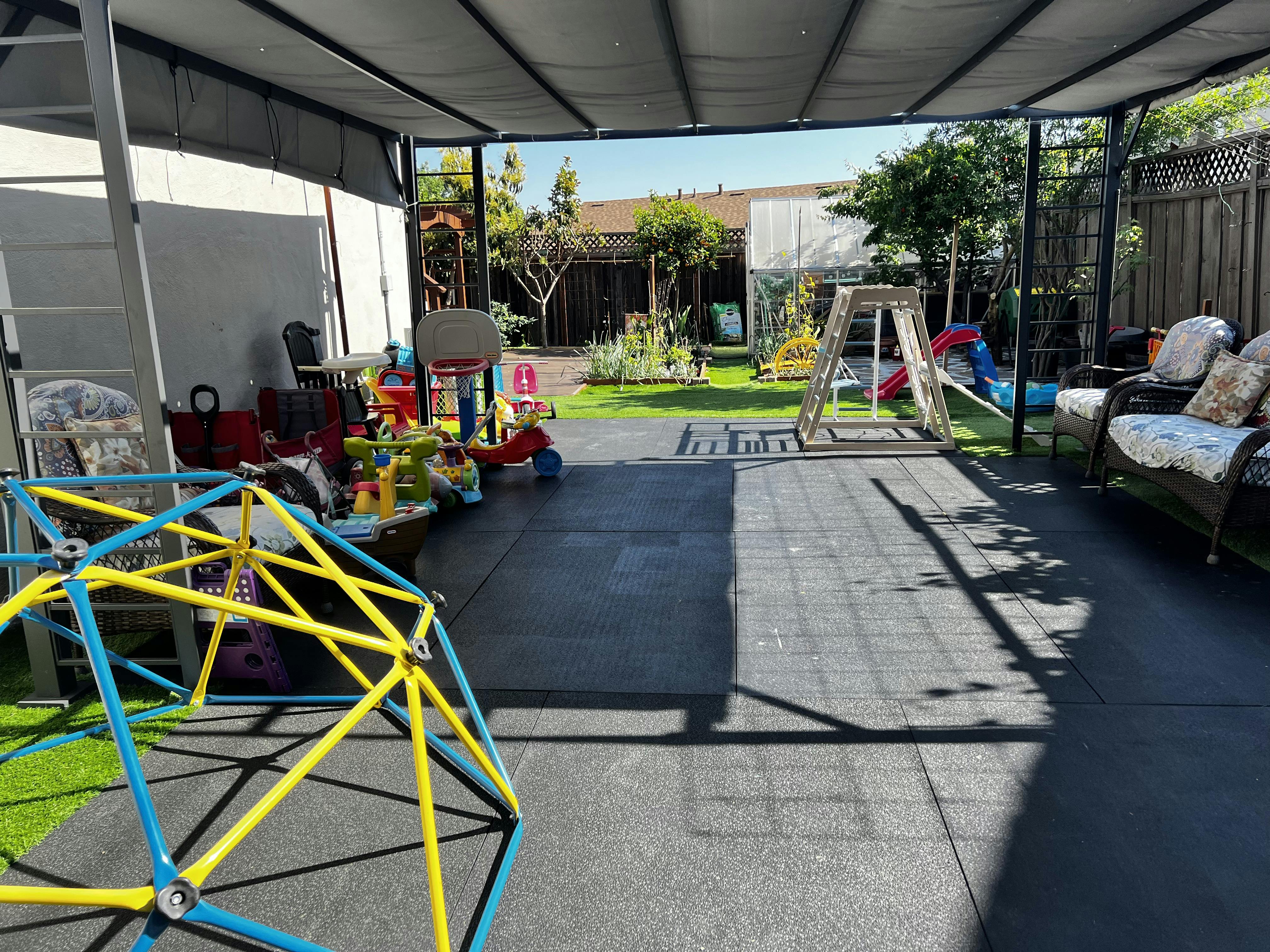 Backyard patio with children playground equipment under a canopy