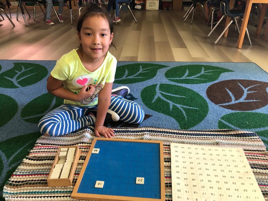 Child sitting on a rug with educational materials