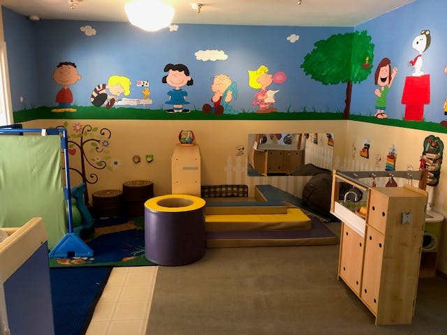 Playroom with cartoon character murals on the wall and play equipment