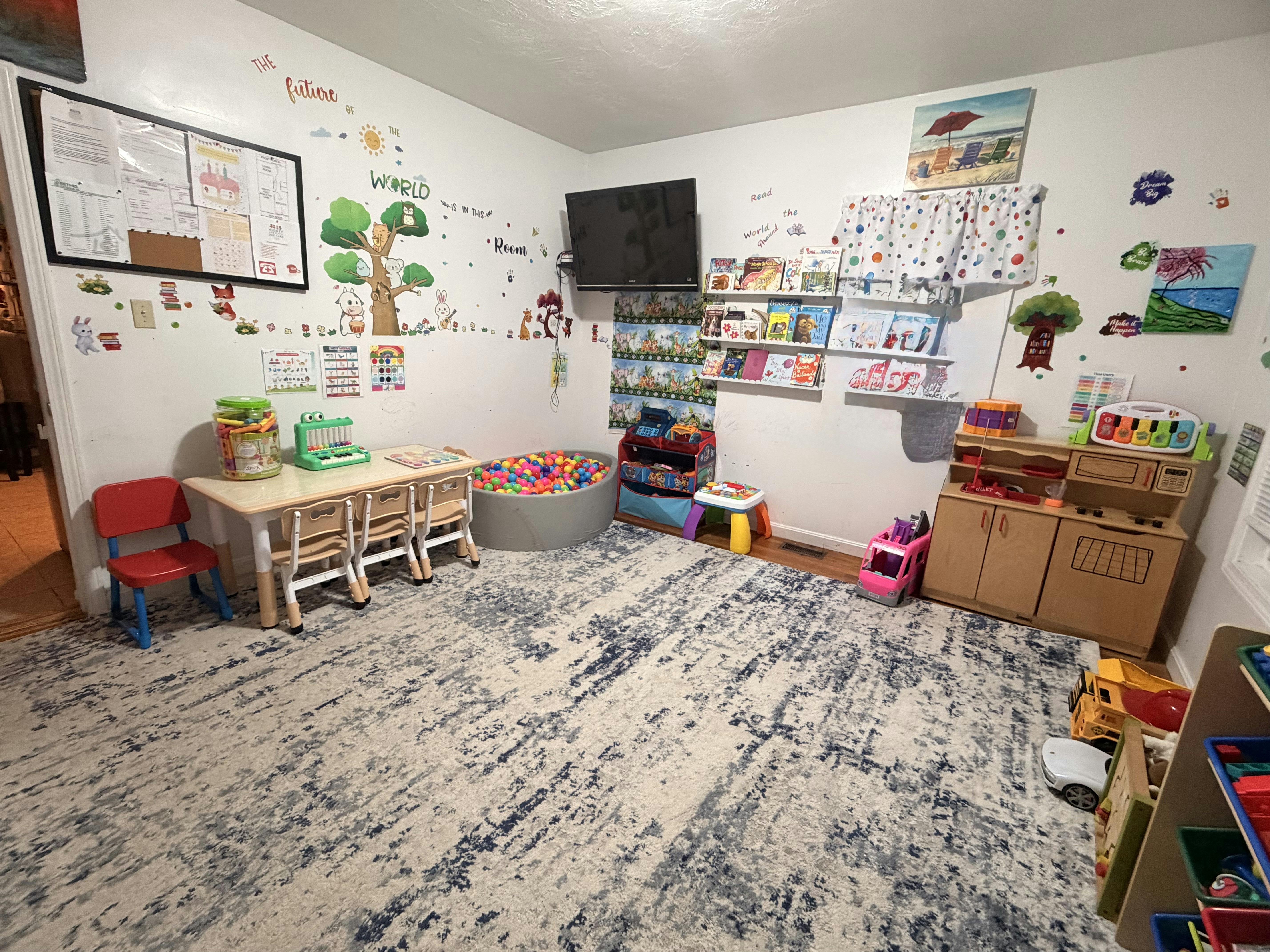 Child's playroom with small tables, chairs, ball pit, and toy kitchen
