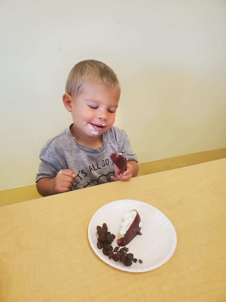 Child with food on face holding a piece of food