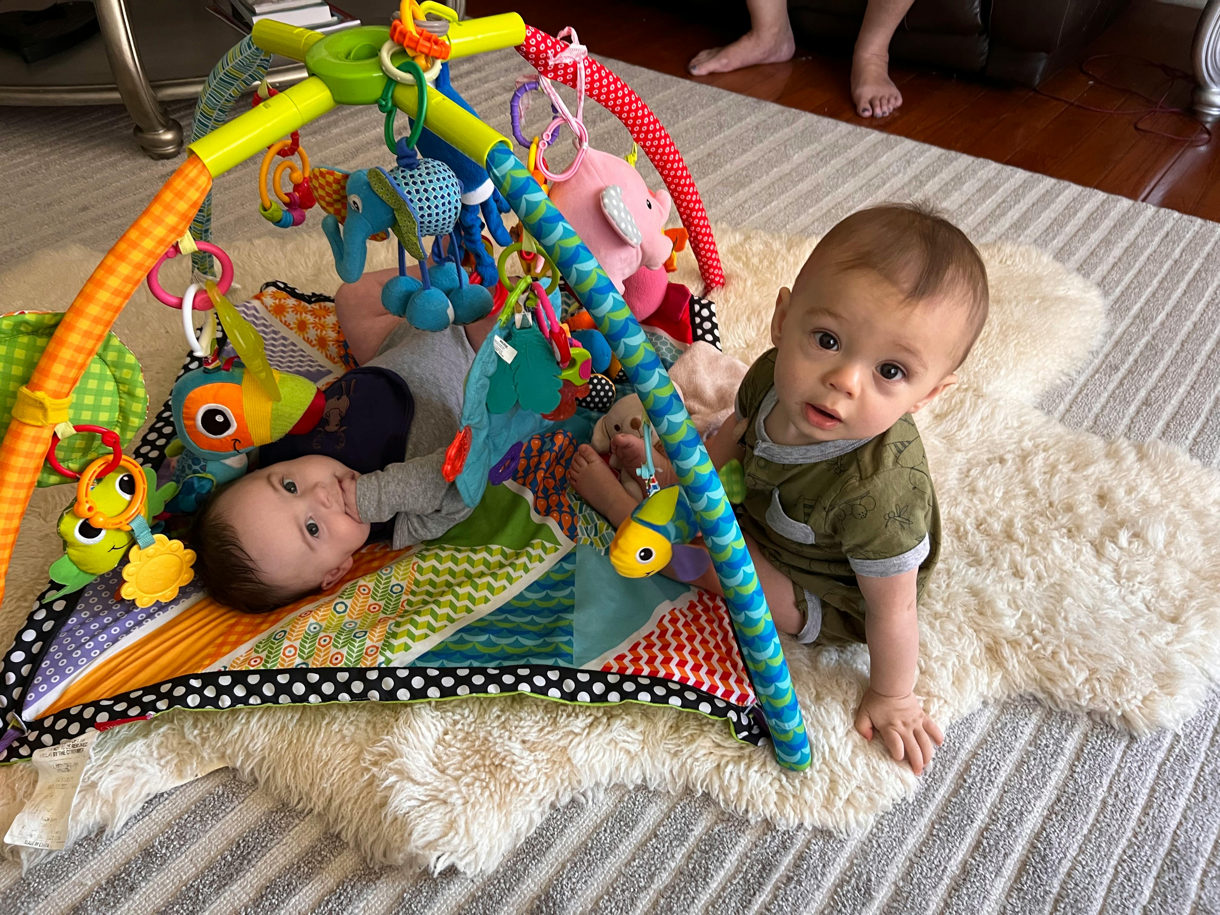 Two babies on a playmat with toys