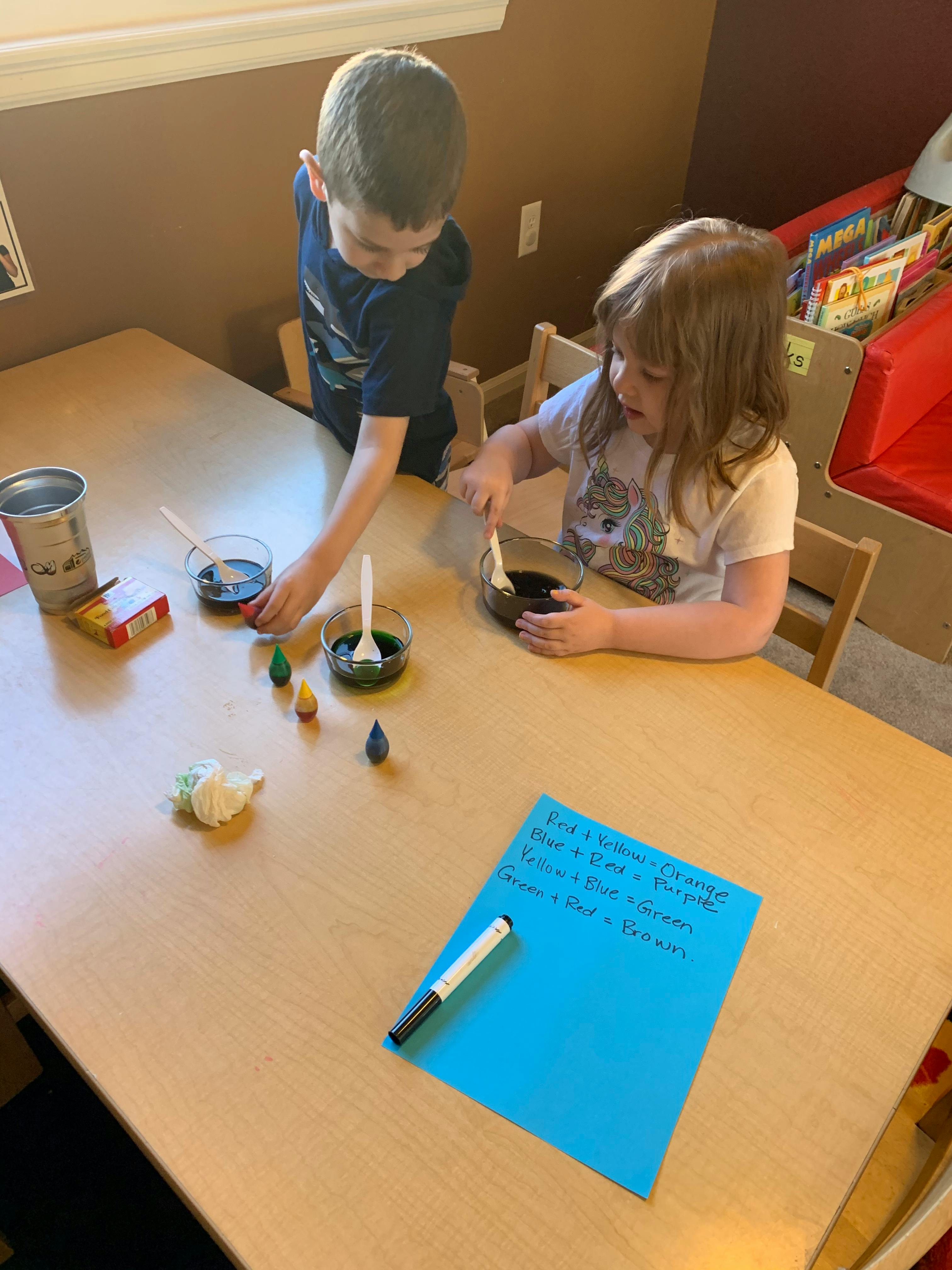 Two children mixing liquids in bowls at a table
