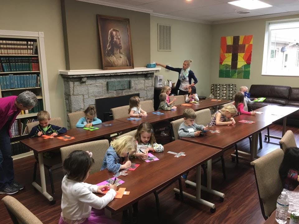 Adults and children sitting at tables in a room