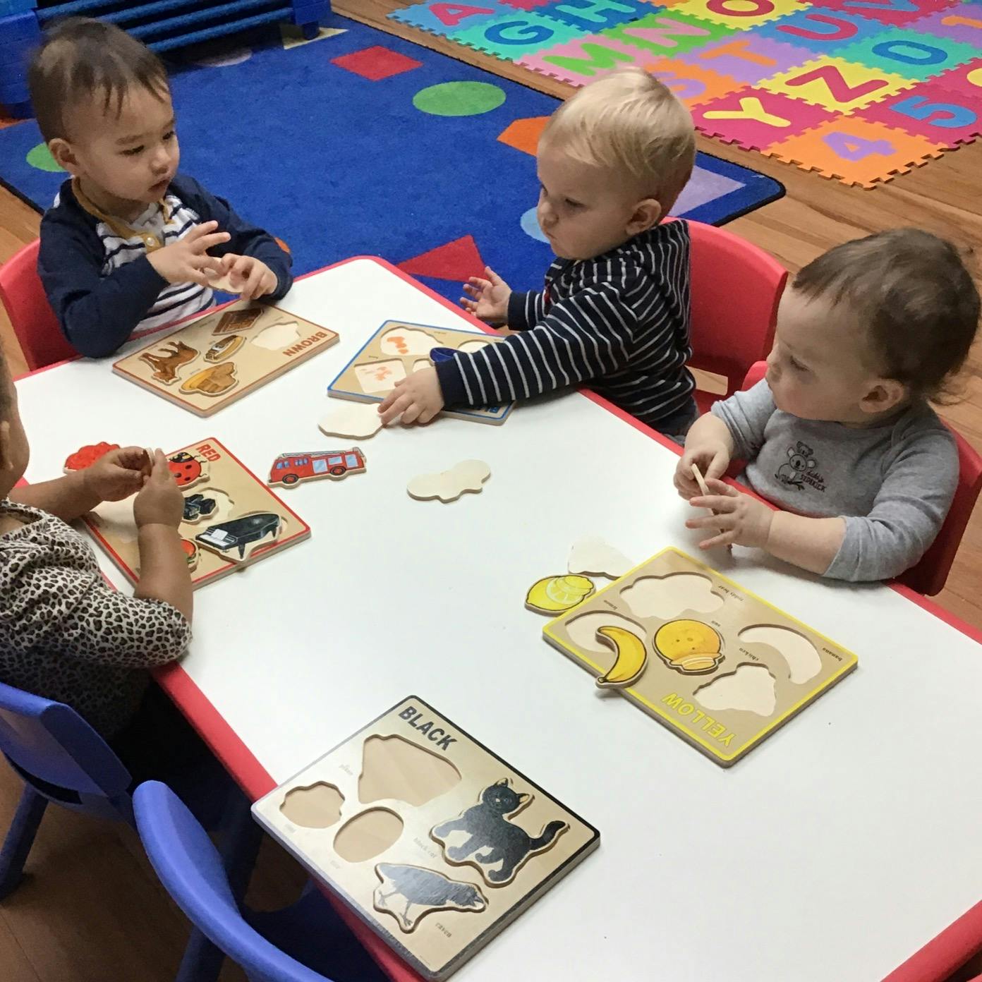 Four children playing with puzzles at a table