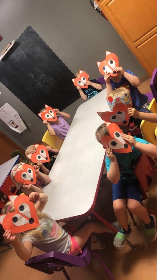 Children wearing fox masks at a table