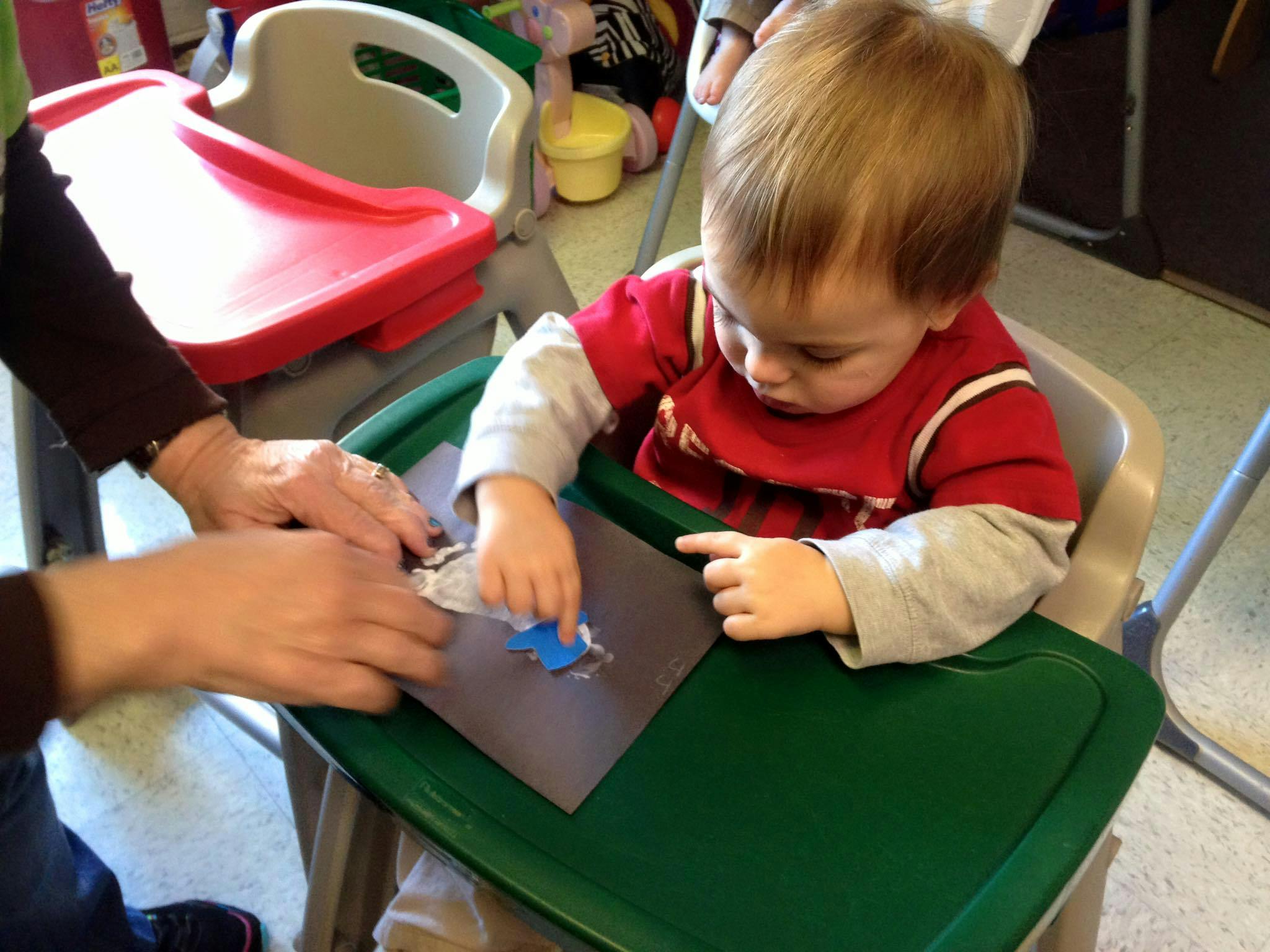 Child in high chair doing an activity with an adult