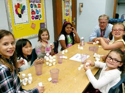Adult and children at a table with small white objects