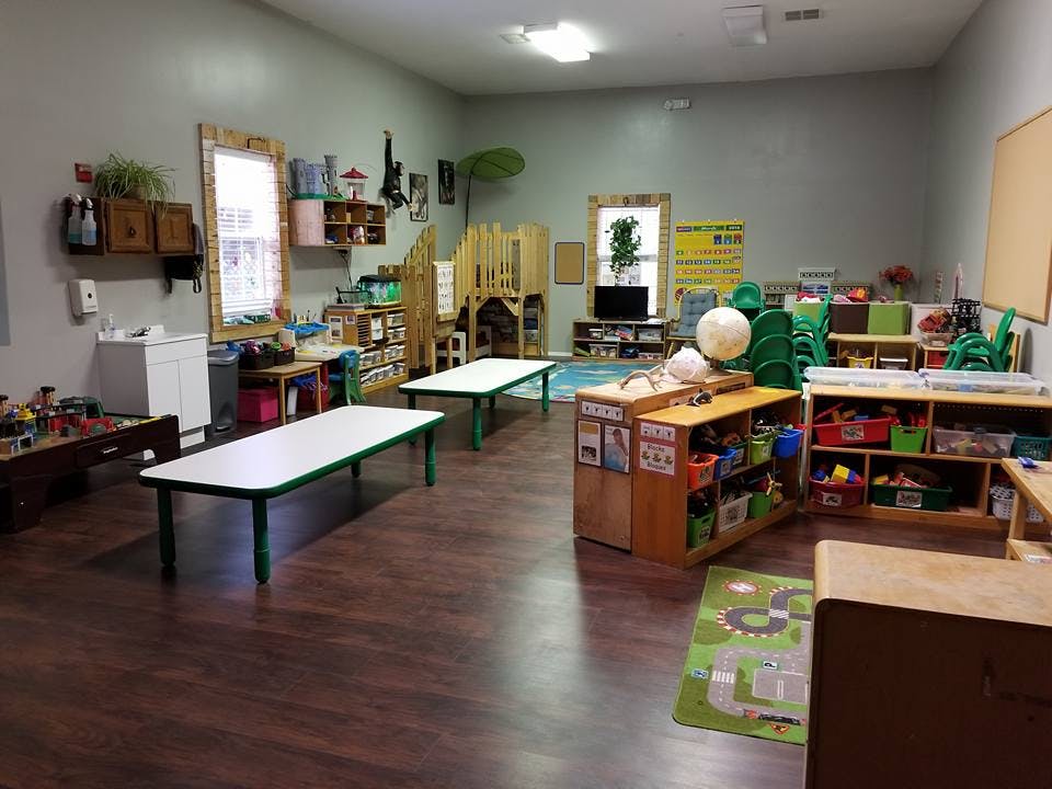 Empty classroom with tables, shelves, and play areas