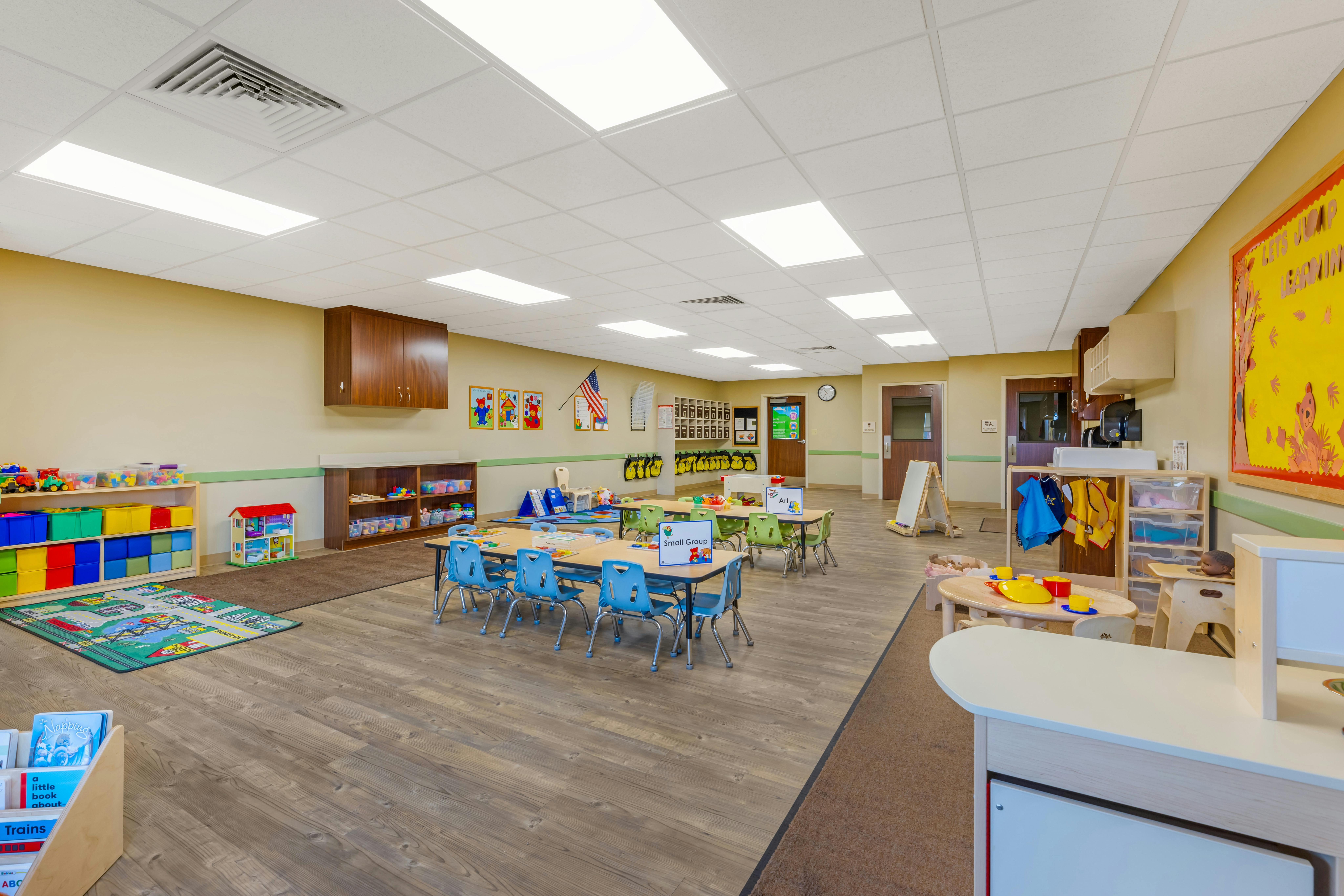 An empty early childhood classroom with multiple small tables and chairs