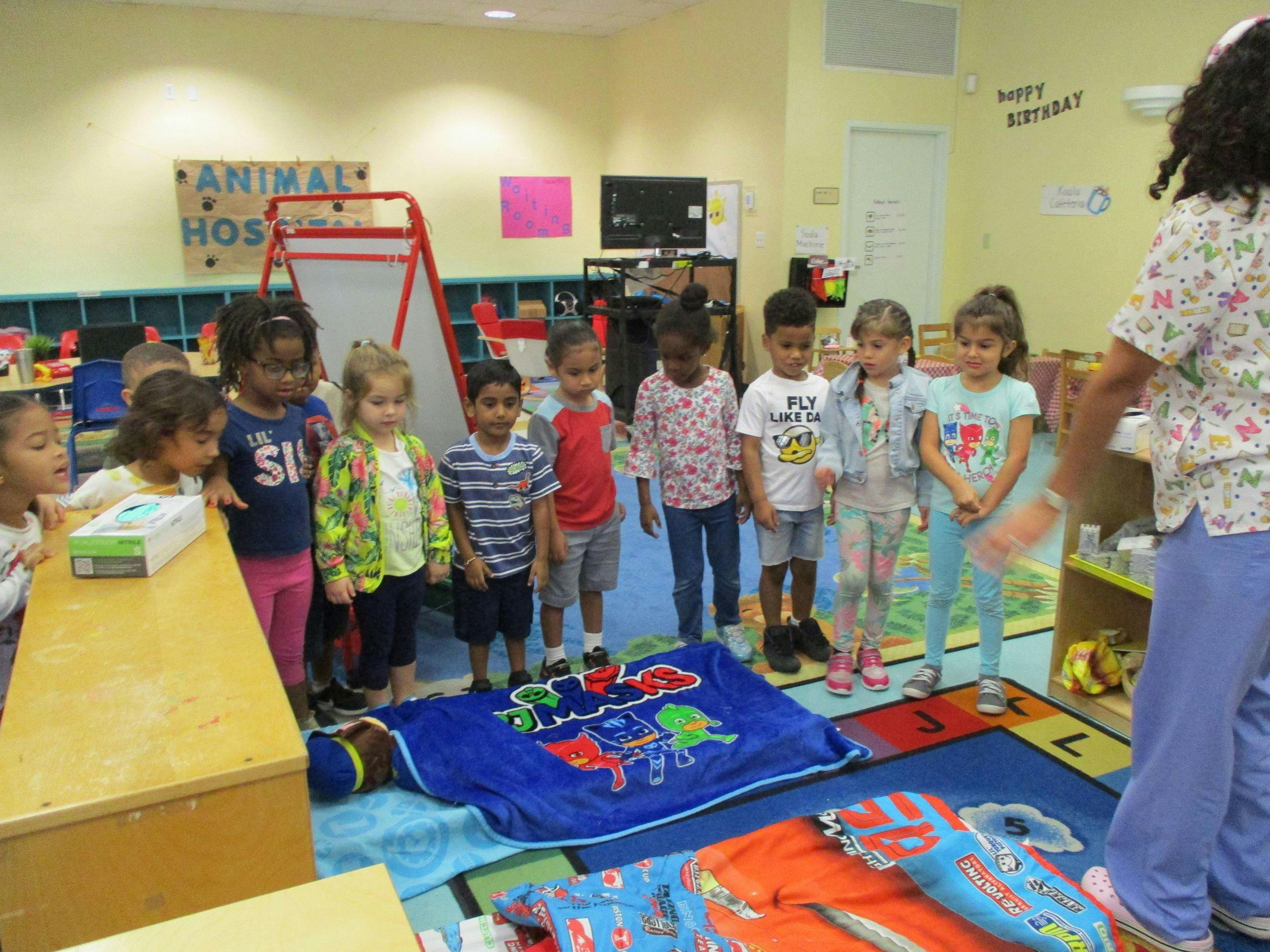 Group of children standing in a classroom with an adult