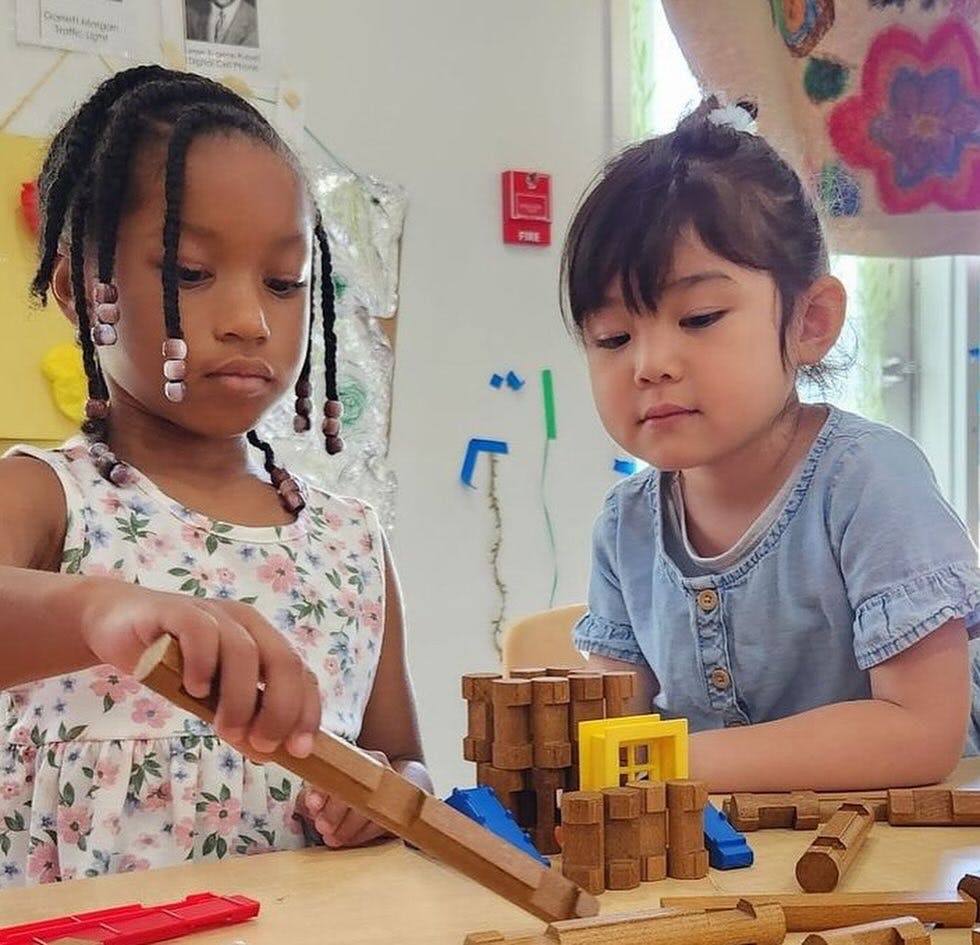 Two children playing with wooden blocks at a table