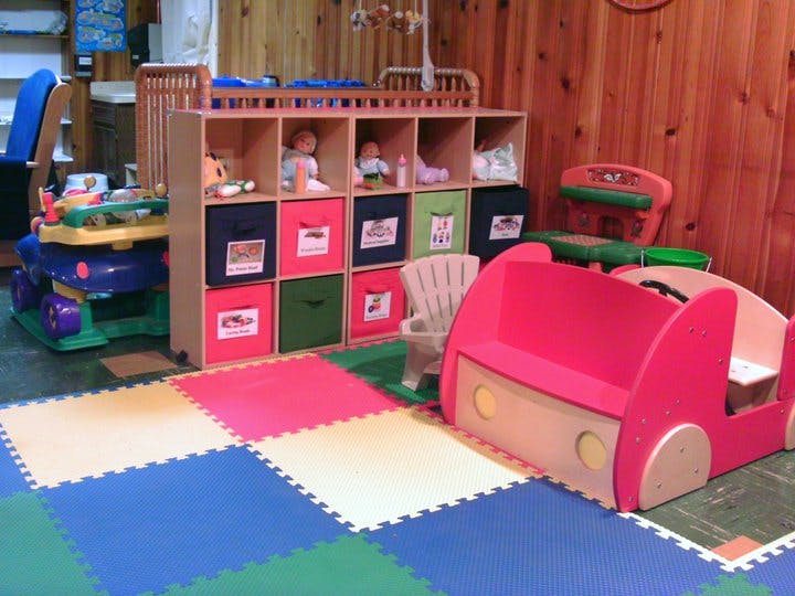 Playroom with colorful floor mats, toy storage, and play furniture
