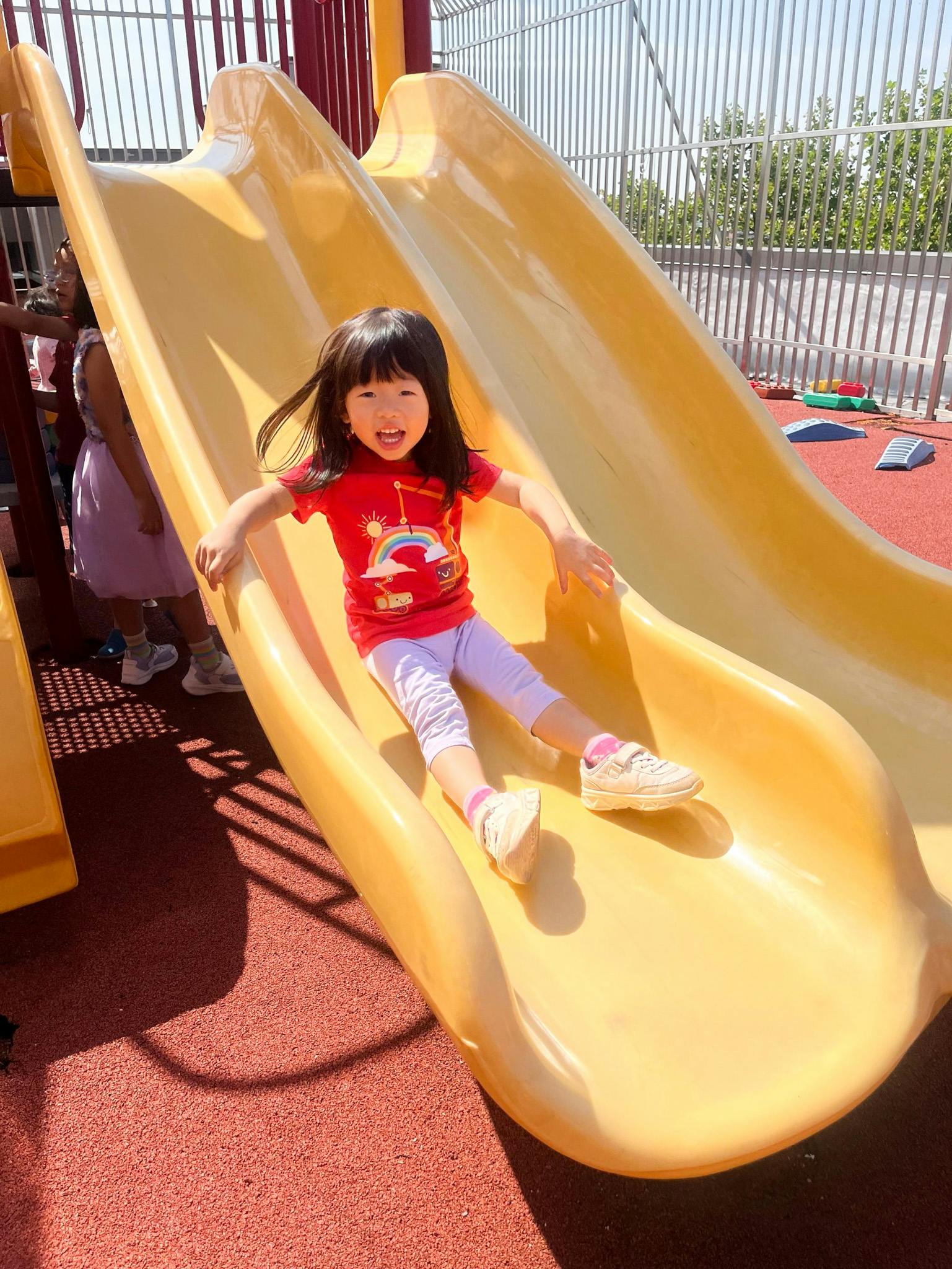 Child sliding down a yellow playground slide