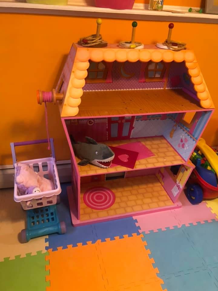 Dollhouse with a toy shark inside and a toy shopping cart next to it