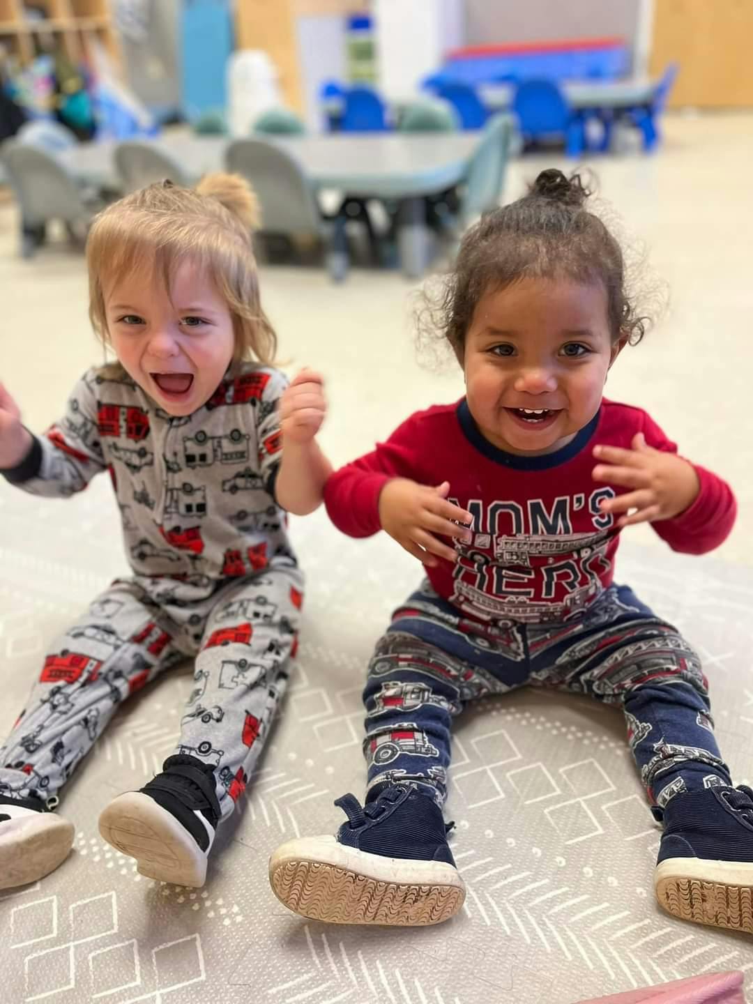 Two children sitting on the floor in a classroom