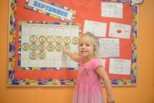Child pointing at a September calendar on a bulletin board