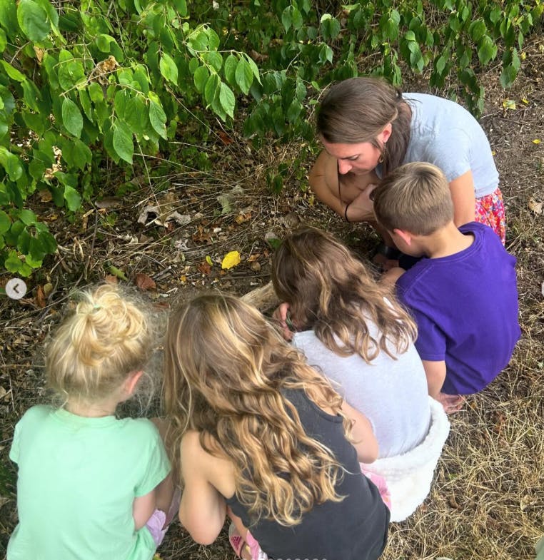 Adult and children looking at something on the ground