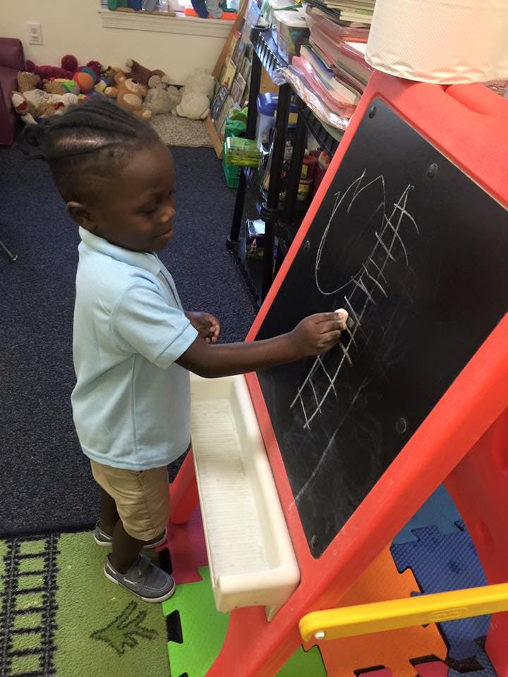 Child drawing on a chalkboard with chalk