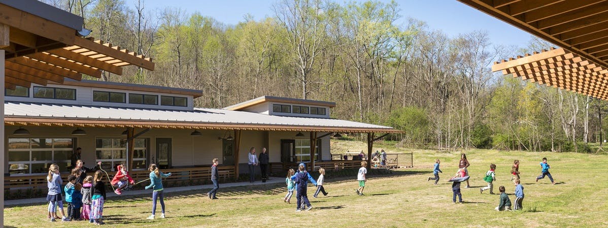 Children playing on a grassy field in front of a building