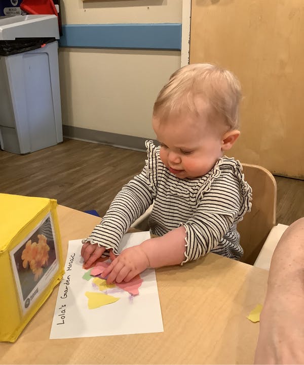 Child playing with paper cutouts on a table